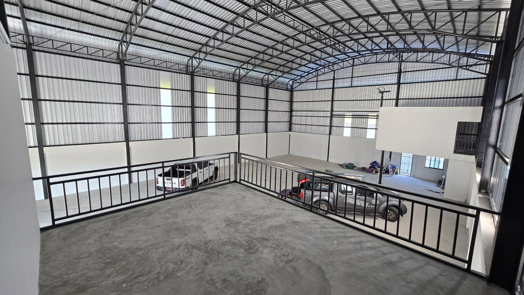 Warehouse for rent in Bang Phli, Samut Prakan - View from the mezzanine platform overlooking the warehouse floor, showing steel trusses and skylight panels.