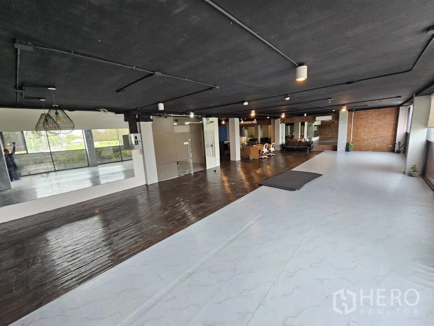Office Space for rent in Watthana, Bangkok - Wide open-plan office showing marble-look white flooring, wooden floor section, glass partitions and mirrors.