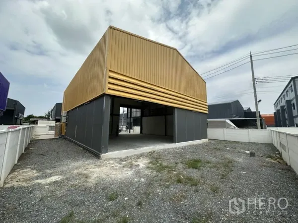 Factory for rent or sale in Bang Yai, Nonthaburi - Rear elevation with open-sided shed and gravel service area.