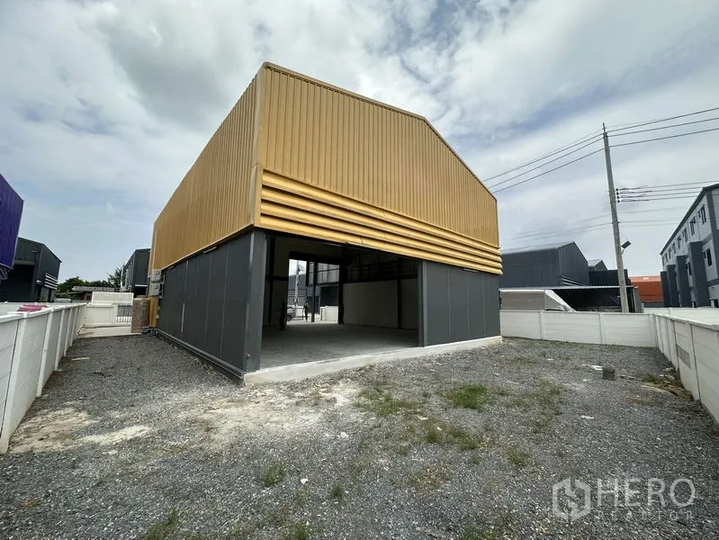 Factory for rent or sale in Bang Yai, Nonthaburi - Rear elevation with open-sided shed and gravel service area.