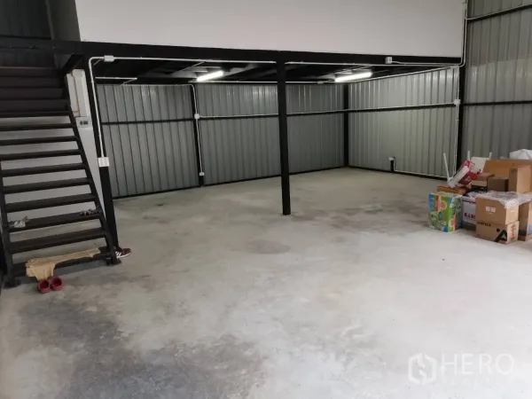 Warehouse for rent in Suan Luang, Bangkok - Open-plan warehouse interior with concrete floor, steel columns, and a side staircase to the mezzanine.