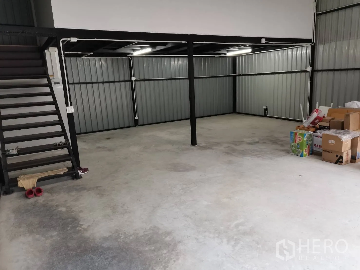 Warehouse for rent in Suan Luang, Bangkok - Open-plan warehouse interior with concrete floor, steel columns, and a side staircase to the mezzanine.