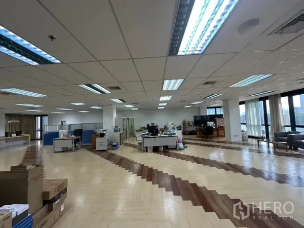 Office Space for rent in Khlong Toei, Bangkok - Large open office floor with desks, grid ceiling and fluorescent lighting, lined with windows capturing lake and skyline views.