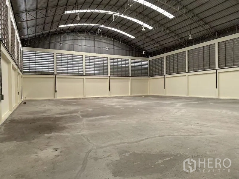 Warehouse for rent in Mueang Samut Sakhon, Samut Sakhon - Spacious warehouse interior with high arched steel roof, skylights, louvered ventilation and smooth concrete floor.