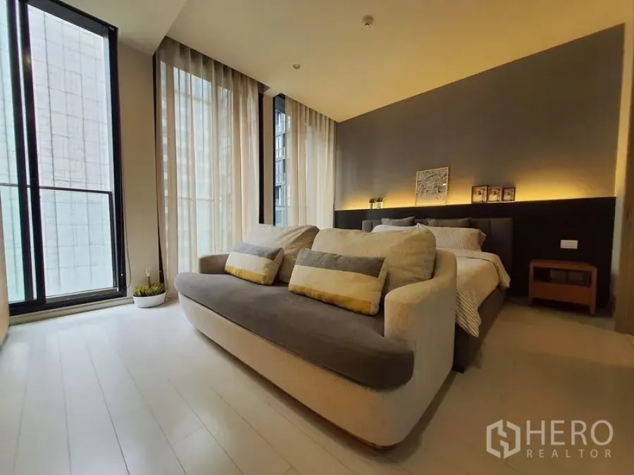 Condominium for rent in Pathum Wan, Bangkok - Bright bedroom-living space with sofa, bed and floor-to-ceiling windows in a modern Bangkok condo.