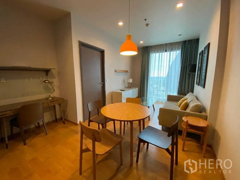 Condominium for rent in Khlong Toei, Bangkok - Dining nook with round table, work desk and access to a balcony through tall sliding doors.