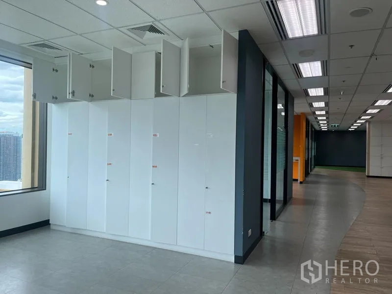 Office Space for rent in Chatuchak, Bangkok - Row of white storage lockers with open overhead cabinets beside a window overlooking Bangkok.