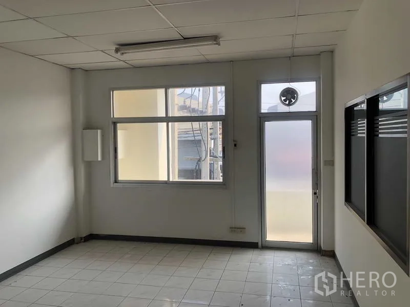 Factory for rent in Khlong Luang, Pathum Thani - Bright tiled office room with large window and frosted glass door.