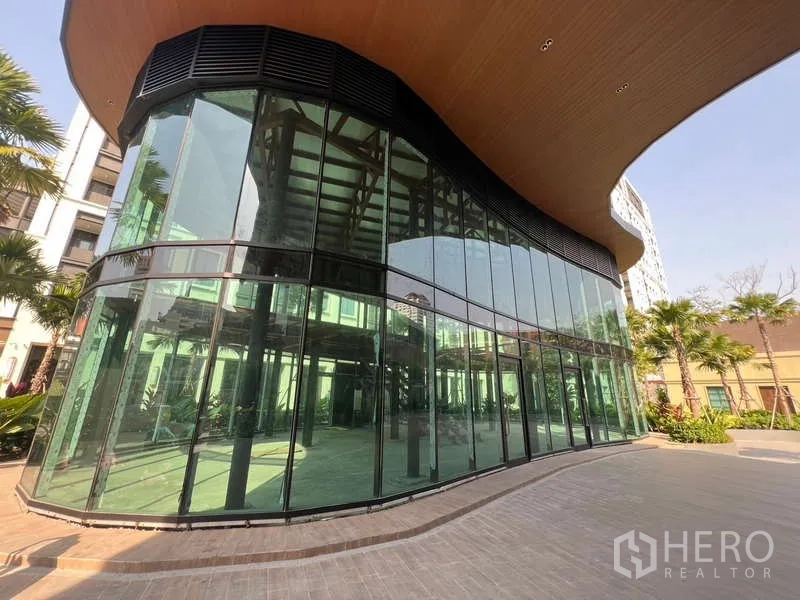 Retail Space for rent in Khlong Toei, Bangkok - Curved glass-front retail pavilion with floor-to-ceiling windows and landscaped walkway in a Sukhumvit complex.