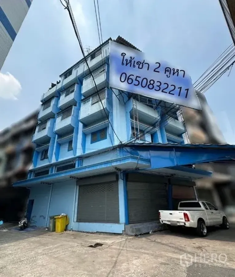 Shophouse for rent in Bang Na, Bangkok - Five-storey corner shophouse with blue facade, balconies and metal shutters in Bang Na.