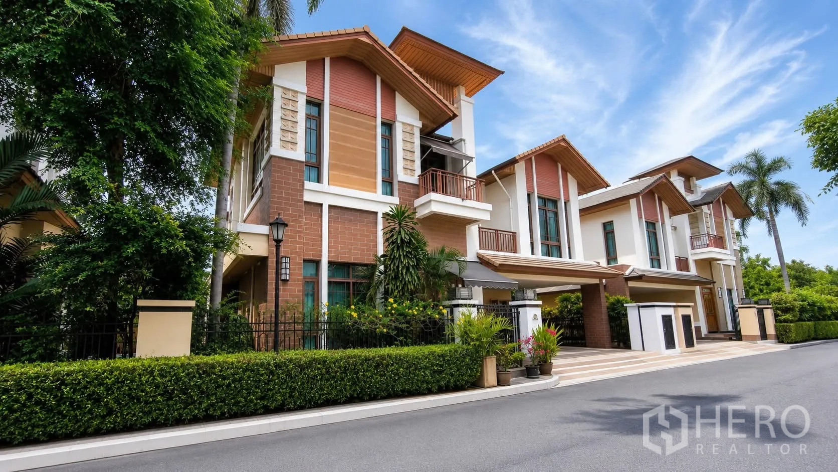 Detached House for rent in Watthana, Bangkok - Front facade of a detached house with balcony and landscaped hedge.