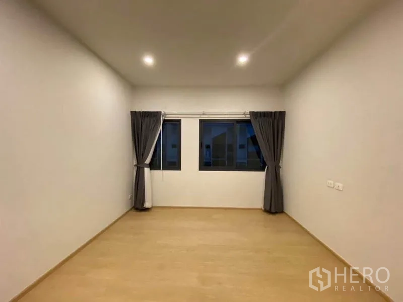 Townhouse for rent in Prawet, Bangkok - Large bedroom with three windows dressed with blackout curtains.