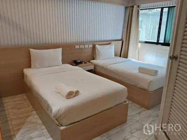 Retail Space for rent in Khlong Toei, Bangkok - Twin-bedded room with bedside table, tiled floor and large window for natural light.