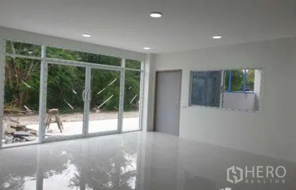 Warehouse for rent in Prawet, Bangkok - Bright ground-floor office or showroom with full-height glass doors and glossy white tile floor.