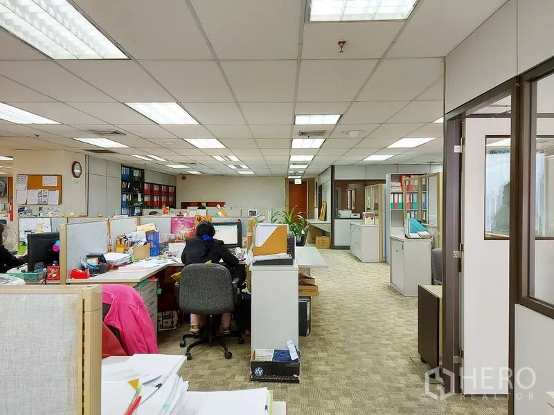 Office Space for rent in Ratchathewi, Bangkok - Carpeted open office with rows of workstations, glass-partition rooms and overhead fluorescent lights for even illumination.