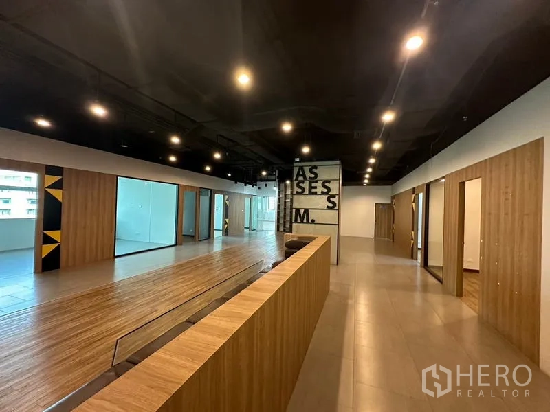 Office Space for rent in Ratchathewi, Bangkok - Open-plan office lobby with wood platform, glass rooms and dark ceiling.