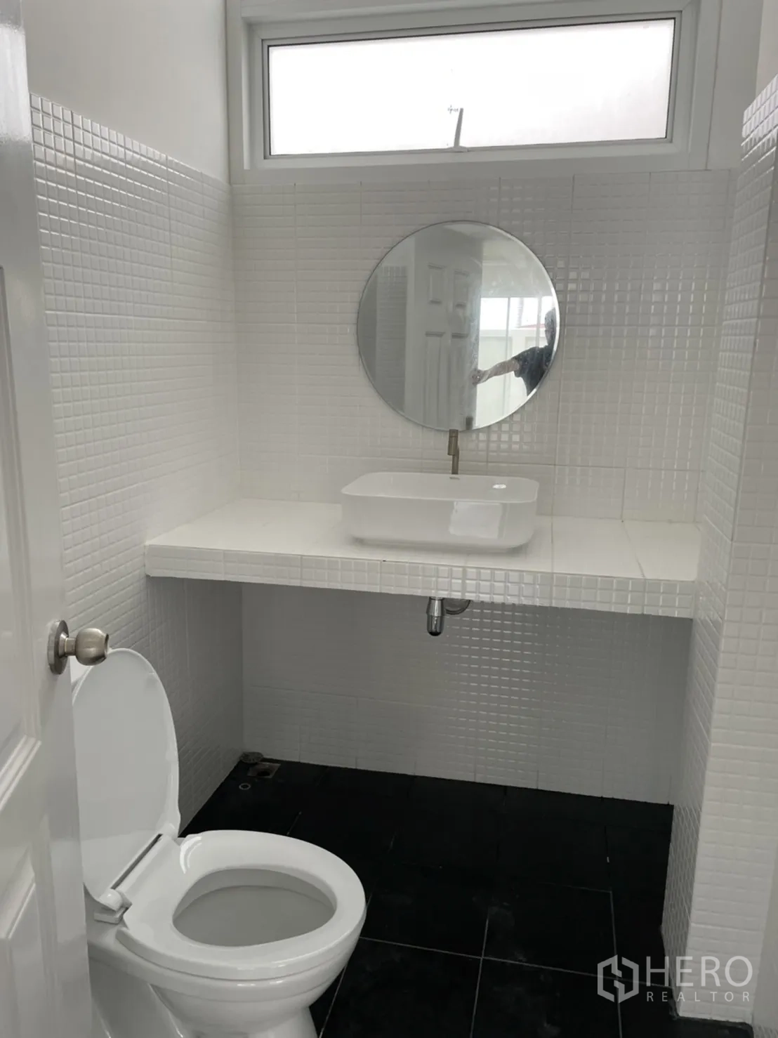 Detached House for rent or sale in Din Daeng, Bangkok - Compact white bathroom with round mirror, countertop basin and window.