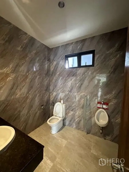 Factory for rent or sale in Lam Luk Ka, Pathum Thani - Bathroom with toilet, urinal and grey marble-style tiles.