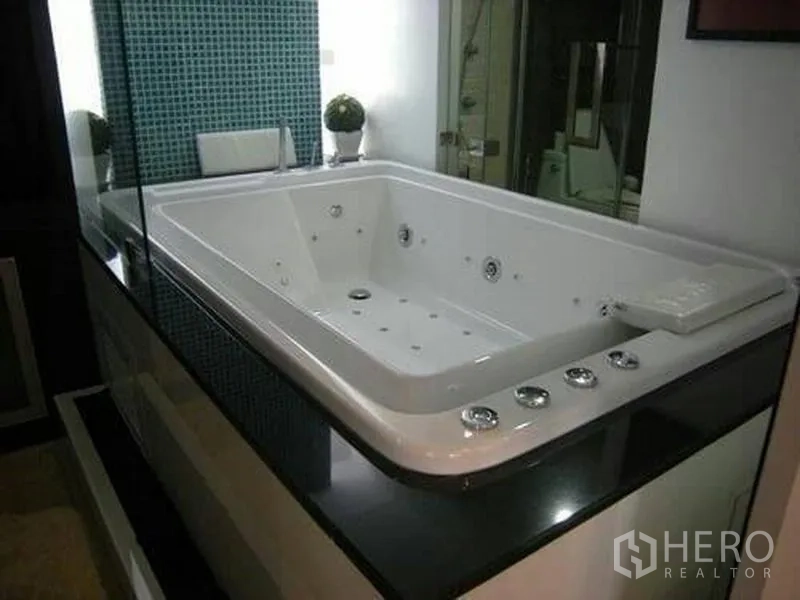 Condominium for rent or sale in Watthana, Bangkok - Close-up of a large built-in jacuzzi bathtub with chrome controls and mosaic tile backdrop.