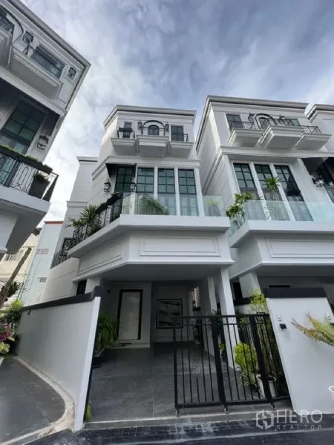 Home Office for rent or sale in Watthana, Bangkok - Three-storey white home office facade with gated carport and large windows.
