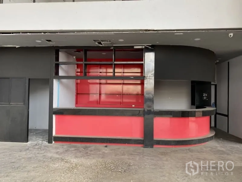 Showroom for rent in Lat Phrao, Bangkok - Ground-floor reception area featuring a red curved counter and open shelving.