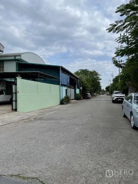 Warehouse for rent in Khan Na Yao, Bangkok - Quiet access road in front of the warehouse with trees and on-street parking.
