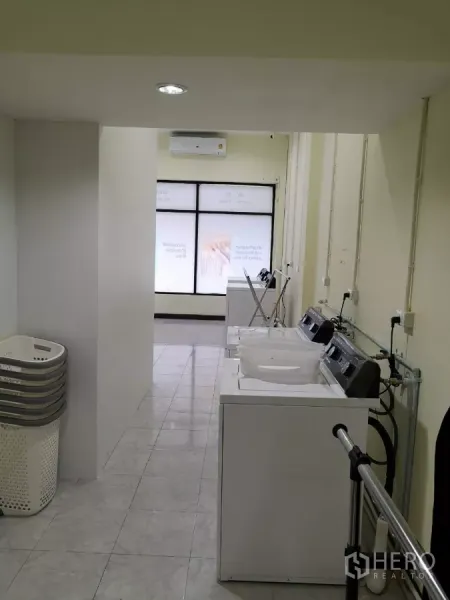 Home Office for rent in Yan Nawa, Bangkok - Bright utility room with tiled floor, air-conditioning and a row of washing machines along one wall.