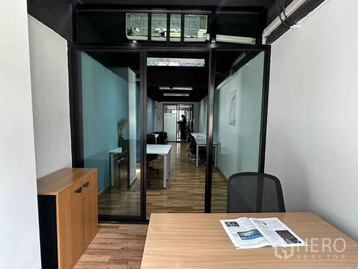 Office Space for rent in Watthana, Bangkok - Glass-partitioned meeting room looking onto open-plan workspace with wood flooring and modern office furniture.