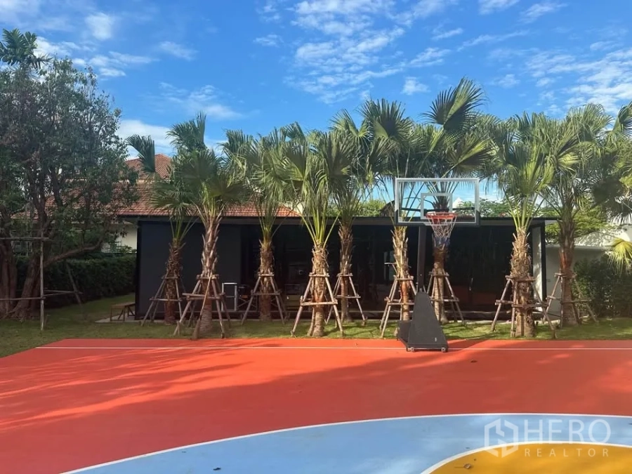 Land for rent in Watthana, Bangkok - Sukhumvit land plot featuring a landscaped garden with palm trees and a colorful outdoor basketball half-court under a blue sky.