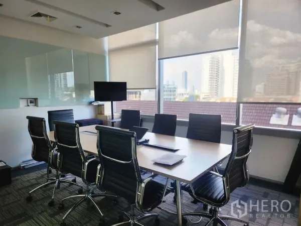 Office Space for rent - Glass-walled boardroom with eight black chairs, TV, whiteboard and city views through large windows.