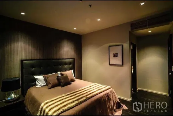 Condominium for rent or sale in Khlong Toei, Bangkok - Cozy bedroom with padded headboard, recessed lighting and warm décor.