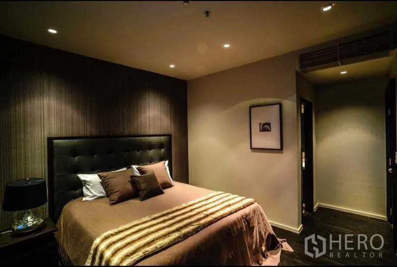 Condominium for rent or sale in Khlong Toei, Bangkok - Cozy bedroom with padded headboard, recessed lighting and warm décor.