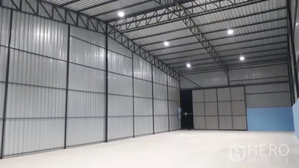 Warehouse for rent in Khlong Luang, Pathum Thani - Spacious warehouse interior with high steel-truss ceiling, bright LED lighting and smooth concrete floor.