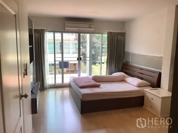 Townhouse for rent or sale in Suan Luang, Bangkok - Master bedroom featuring king bed, large sliding doors to balcony, AC unit and natural light.