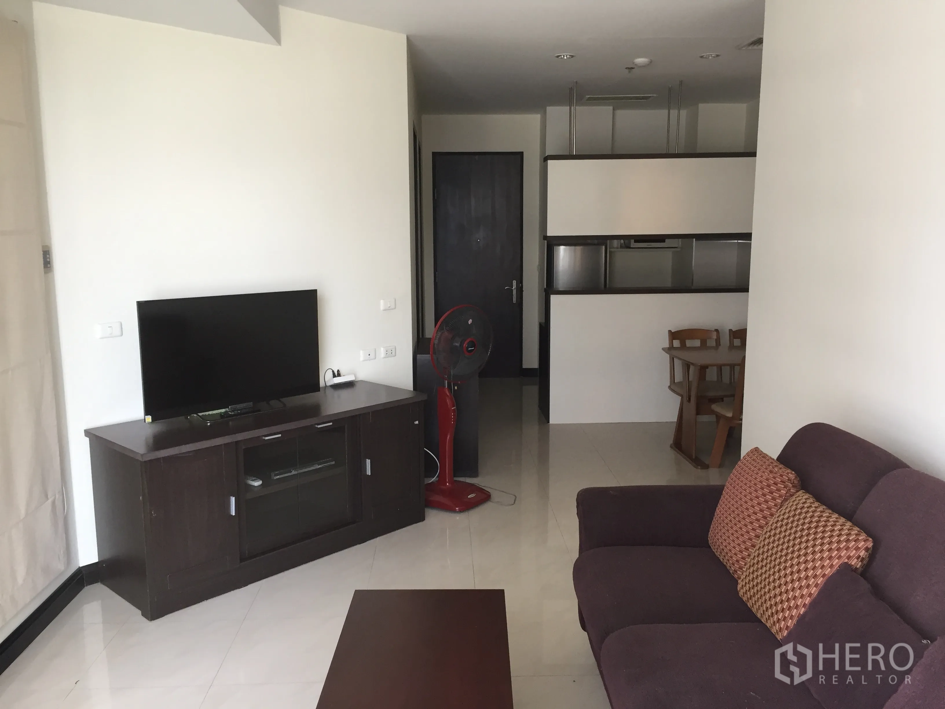 Condominium for rent in Khlong Toei, Bangkok - Bright living room with TV console, sofa and tiled flooring in a modern Bangkok condo.