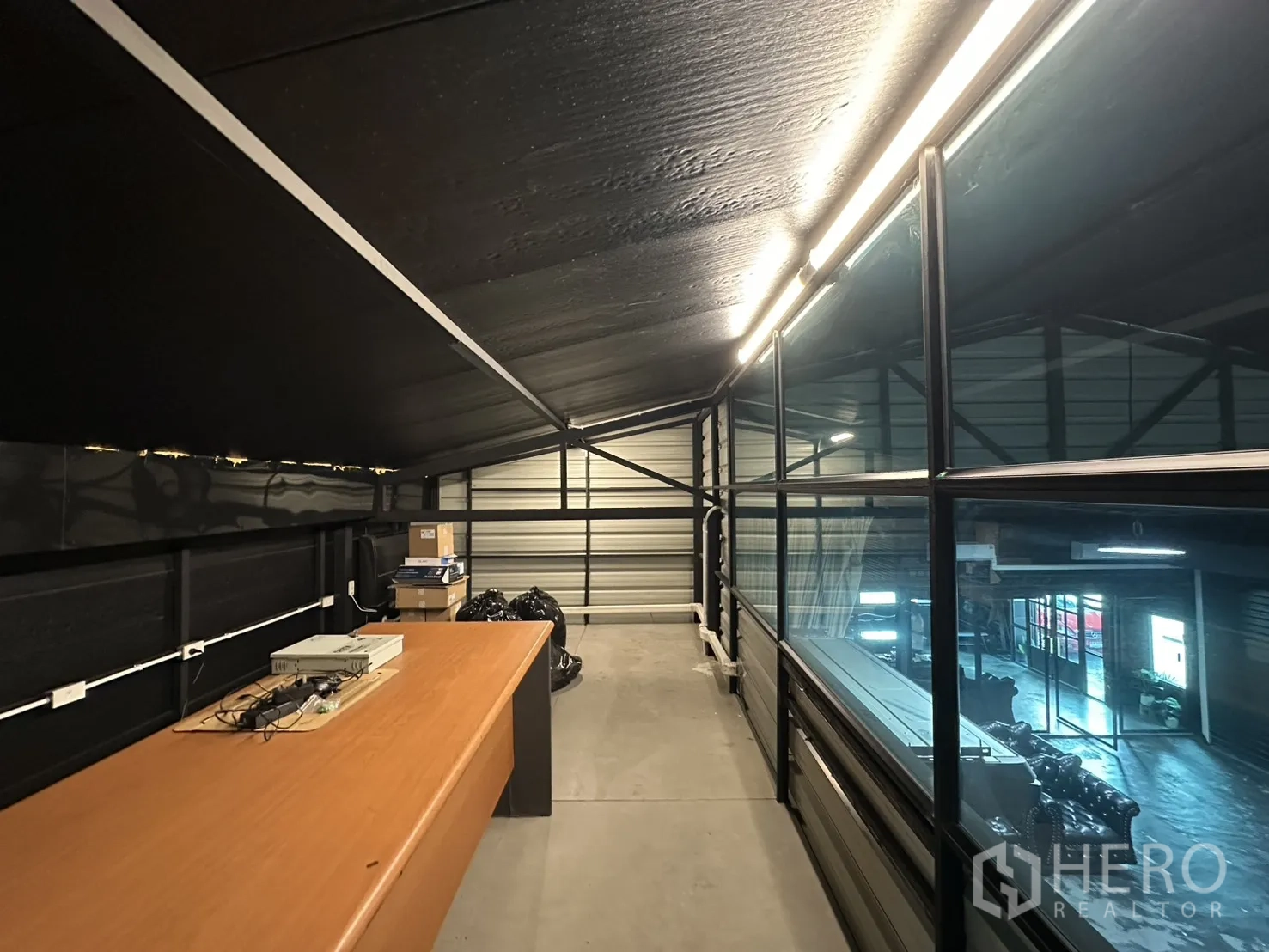 Warehouse for rent in Phra Khanong, Bangkok - Glass-partitioned mezzanine workspace with a long desk overlooking the hall.