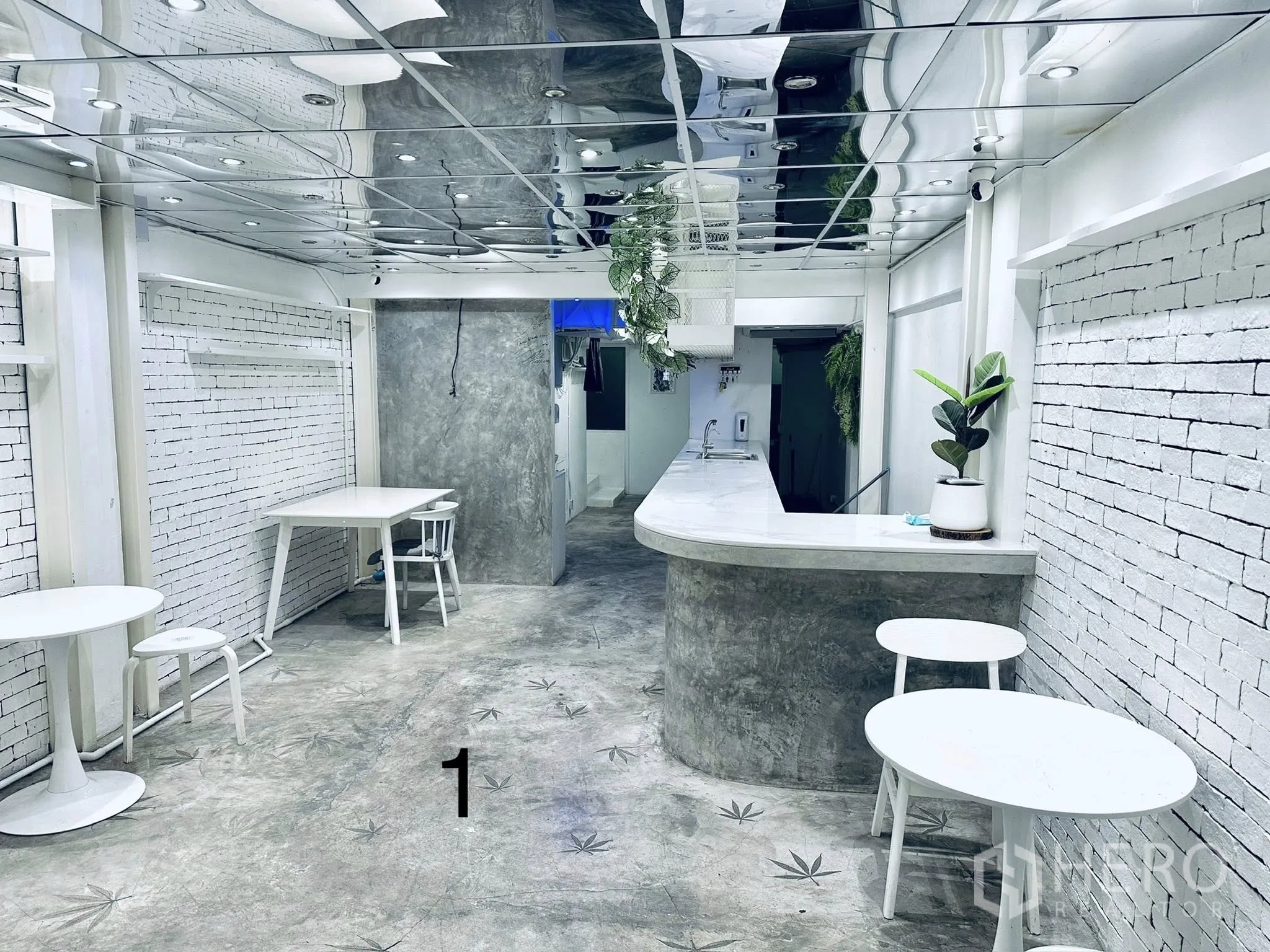 Shophouse for rent in Watthana, Bangkok - Ground-floor space with a curved concrete counter, white brick walls, round tables, and a mirrored ceiling.