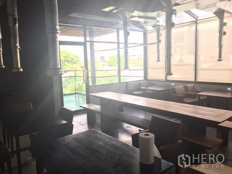 Retail Space for rent in Watthana, Bangkok - Bright dining room with floor-to-ceiling windows, wooden benches and terrace access.