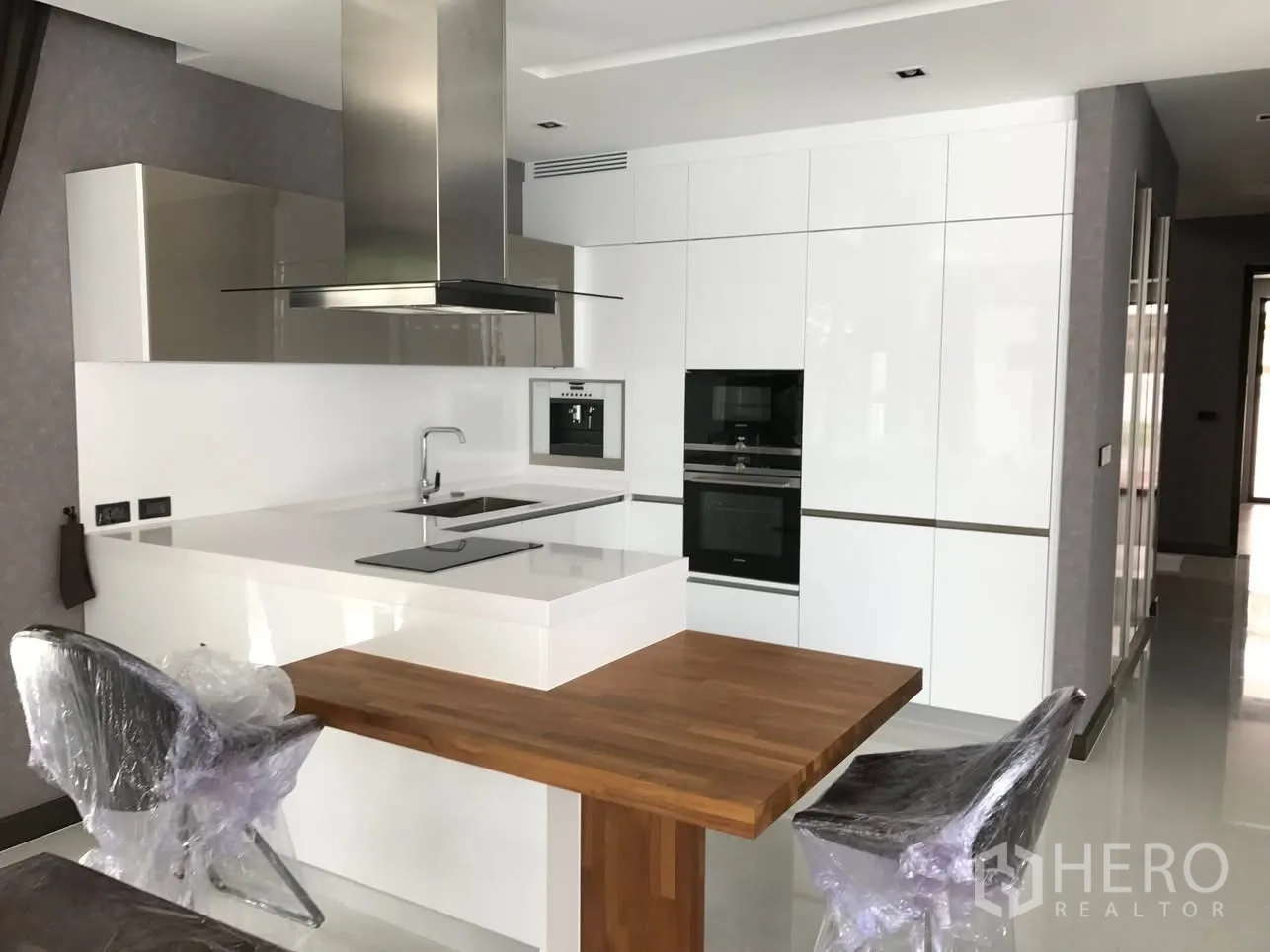Detached House for rent in Bang Kapi, Bangkok - Sleek white European kitchen with island cooktop, range hood, and built-in ovens.