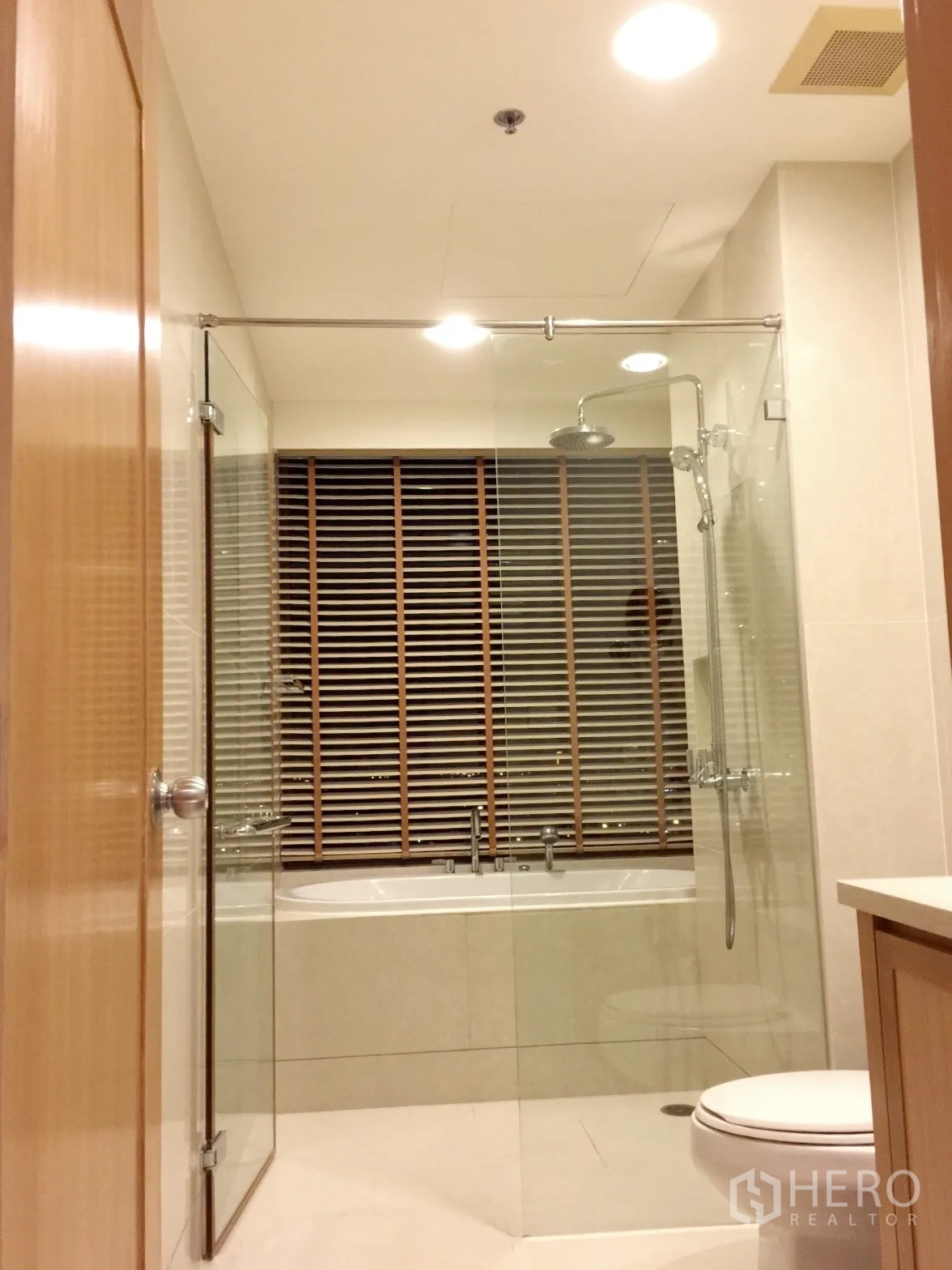 Condominium for rent or sale in Khlong Toei, Bangkok - Bathroom with glass shower enclosure, bathtub and neutral tiling.