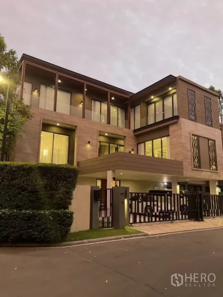 Detached House for rent or sale in Bang Kapi, Bangkok - Evening view of the luxury house exterior with warm lights and secure gate.