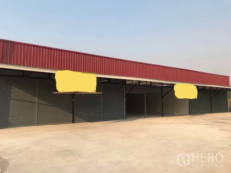 货栈 出租在Lam Luk Ka, Pathum Thani - 仓库排建筑正面，红色檐板与多樘卷帘门。