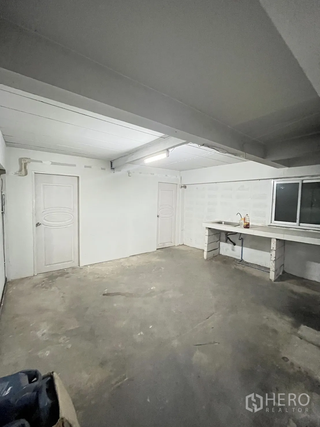 Warehouse for rent in Chatuchak, Bangkok - Small interior room with two doors, a window, and a built-in sink.