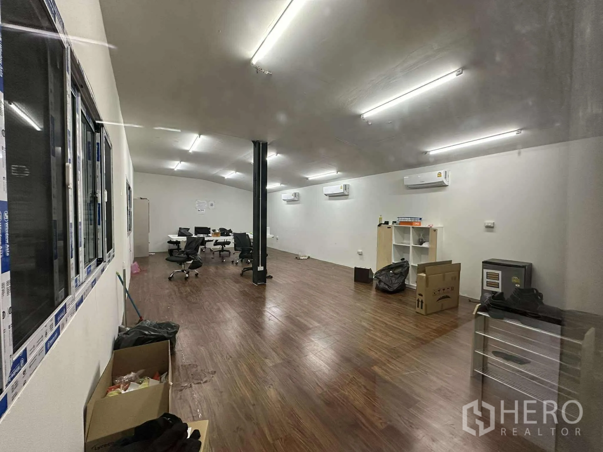 Warehouse for rent - Finished office floor with wooden flooring, multiple AC units, bright lights and workstations.