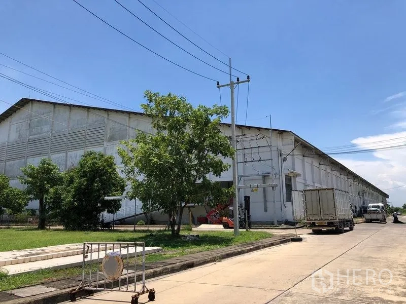 Factory for rent in Lat Krabang, Bangkok - Corner view of the industrial complex with trucks, greenery and overhead power lines.