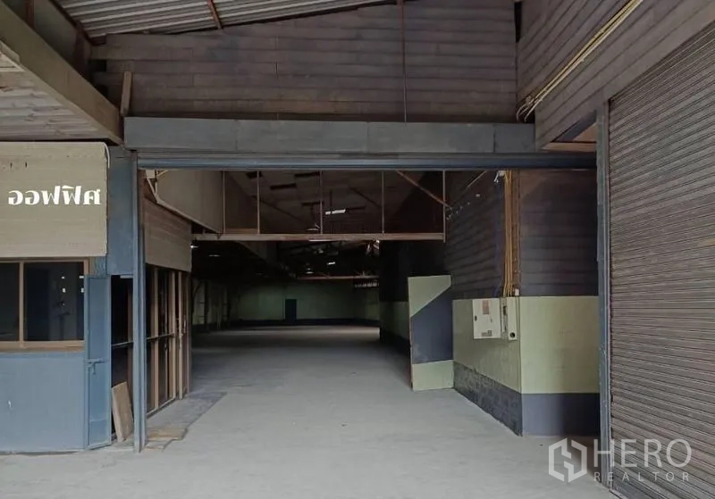 Warehouse for rent in Bang Khen, Bangkok - Warehouse entrance in Bang Khen with roller shutter, office booth and wide concrete floor.
