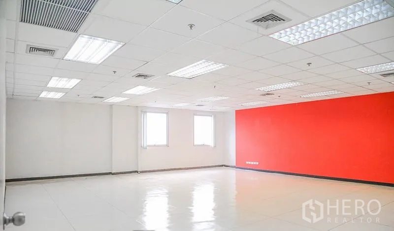 Office Space for rent in Bang Na, Bangkok - Open office area with two windows, a red feature wall, and grid ceiling lights.