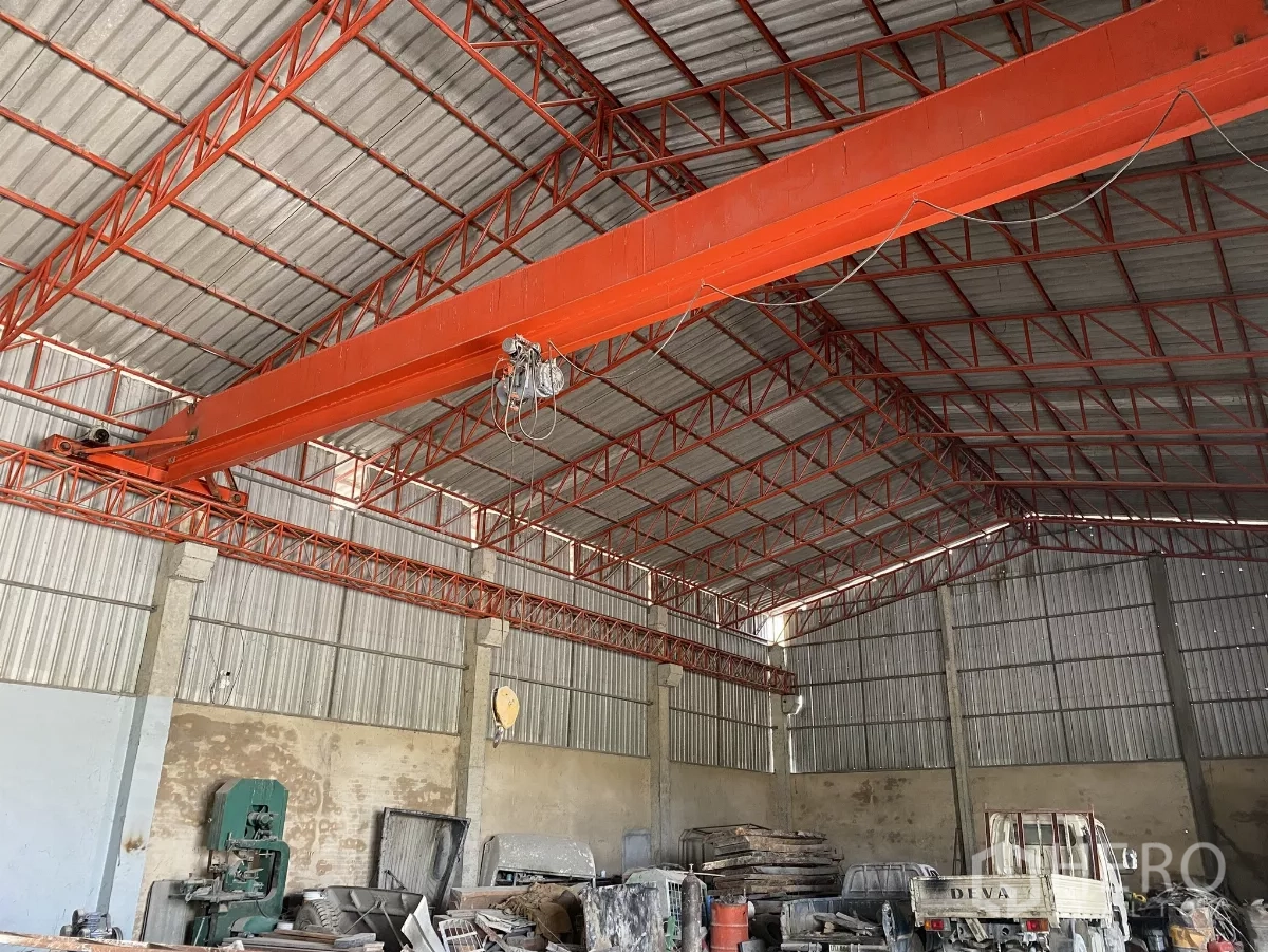 Factory for sale in Chon Buri - Interior roof structure showing red steel trusses and an overhead bridge crane above the workshop floor.
