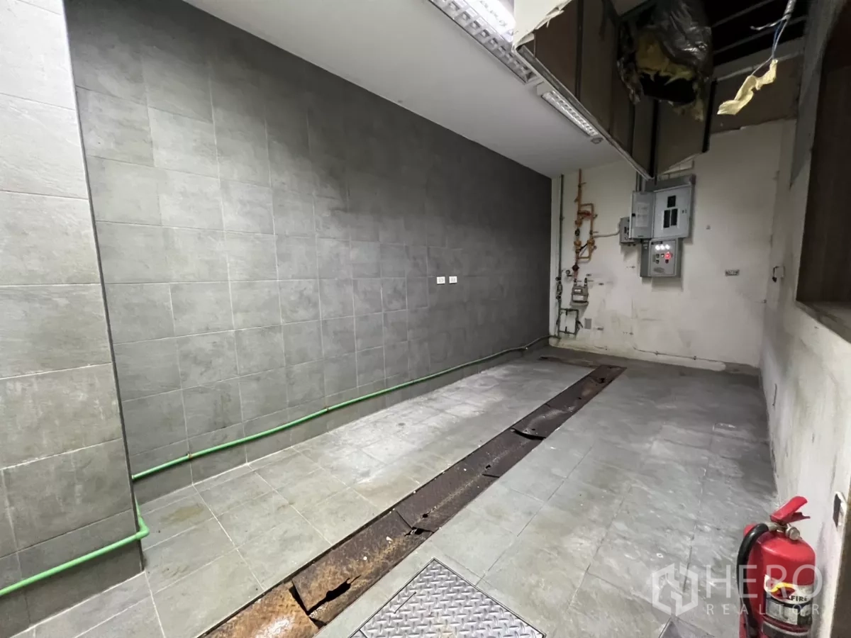 Retail Space for rent - Another view of tiled BOH kitchen with green water pipe, trench drain and fire extinguisher.