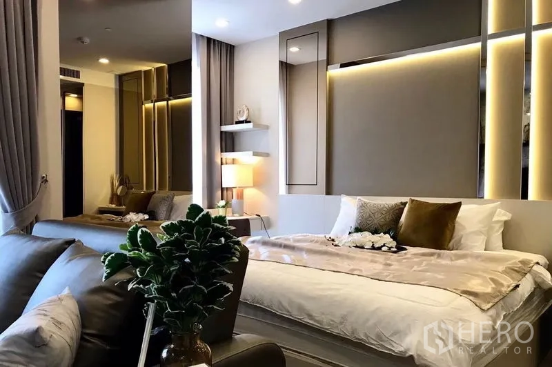 Condominium for rent in Watthana, Bangkok - Open-plan one-bedroom layout showing bed, sofa seating, and soft LED accent lighting.